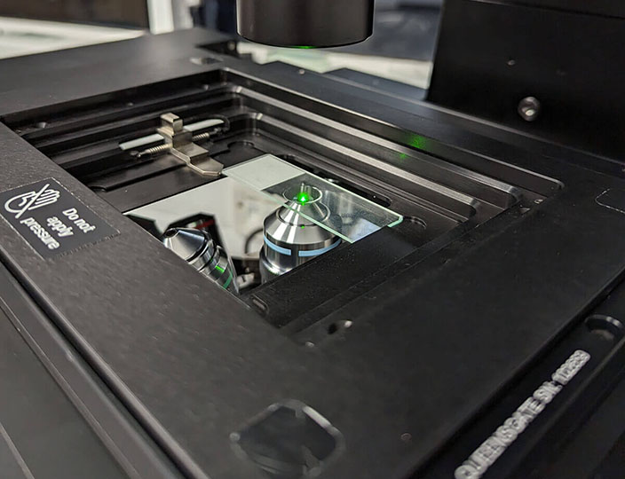 A close up of an inverted microscope fitted with a Prior motorized XY stage and a Queensgate SP series piezo nanopositioning Z stage.